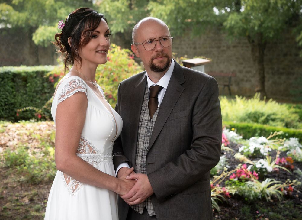 Tender moment shared in a lush garden setting with flowers and greenery creating a romantic backdrop.