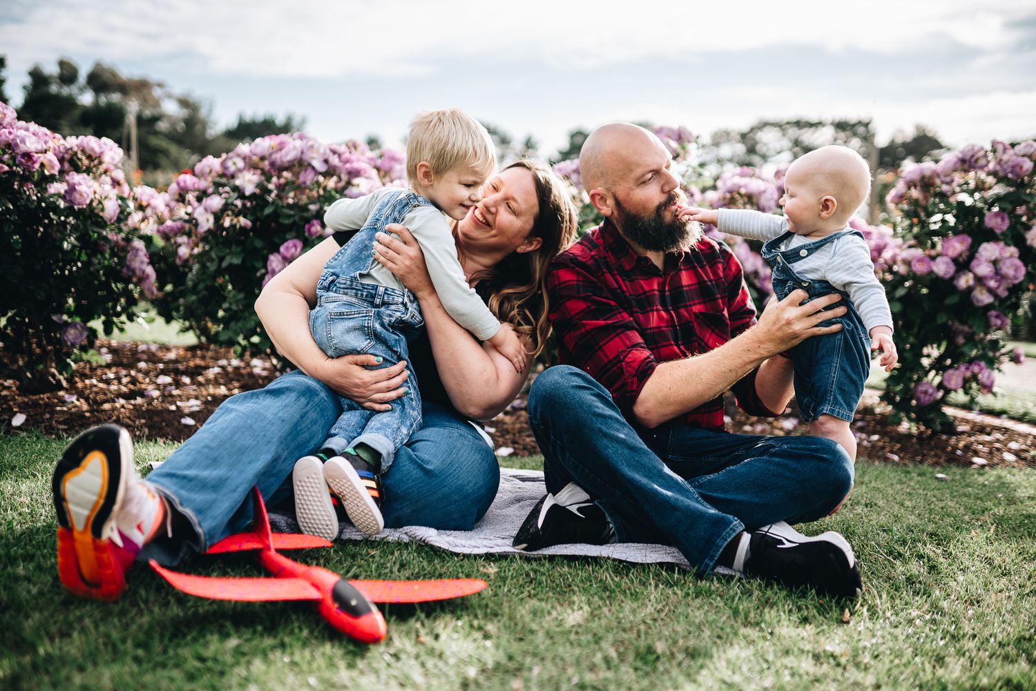 Family lounges together and shares sweet moments in a blooming garden during Melbourne springtime photo session.