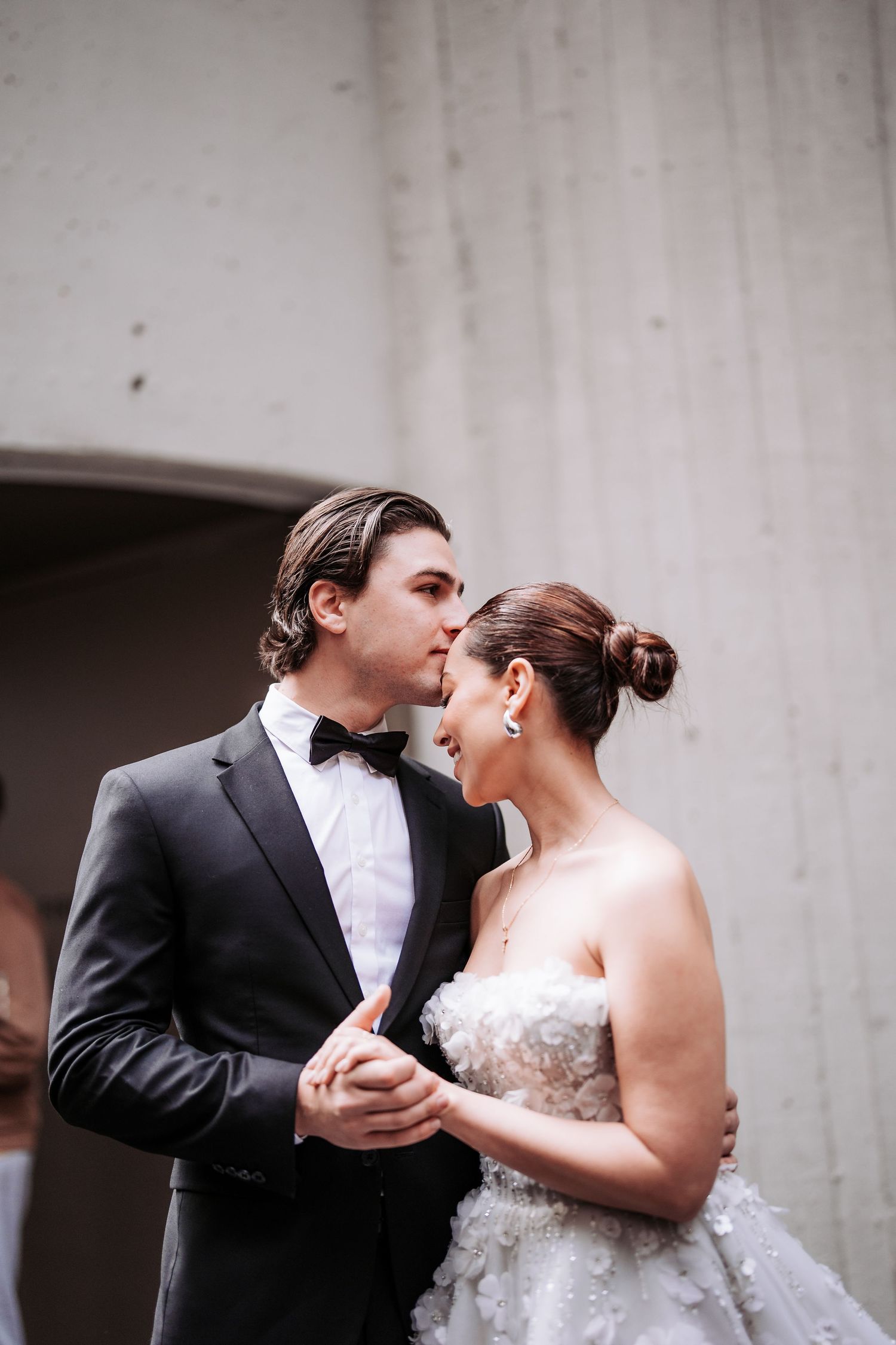 A romantic sequence of wedding photos showing a couple dancing intimately in formal attire against a concrete wall.