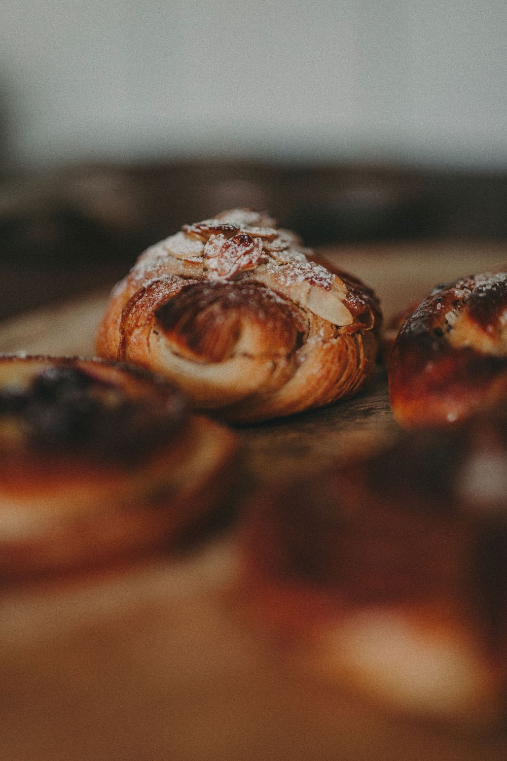 Fresh baked chocolate croissants cooling on a wooden surface with shallow depth of field.