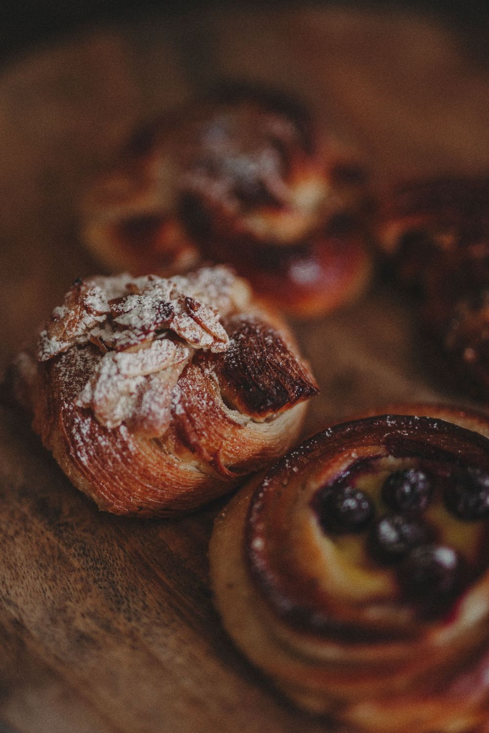 Close-up of freshly baked chocolate pastries dusted with powdered sugar on a rustic wooden surface.