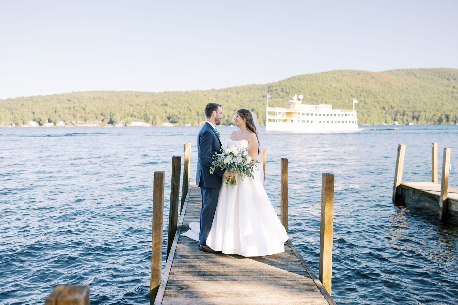 Couple shares romantic moments on a wooden dock overlooking a serene lake at sunset.