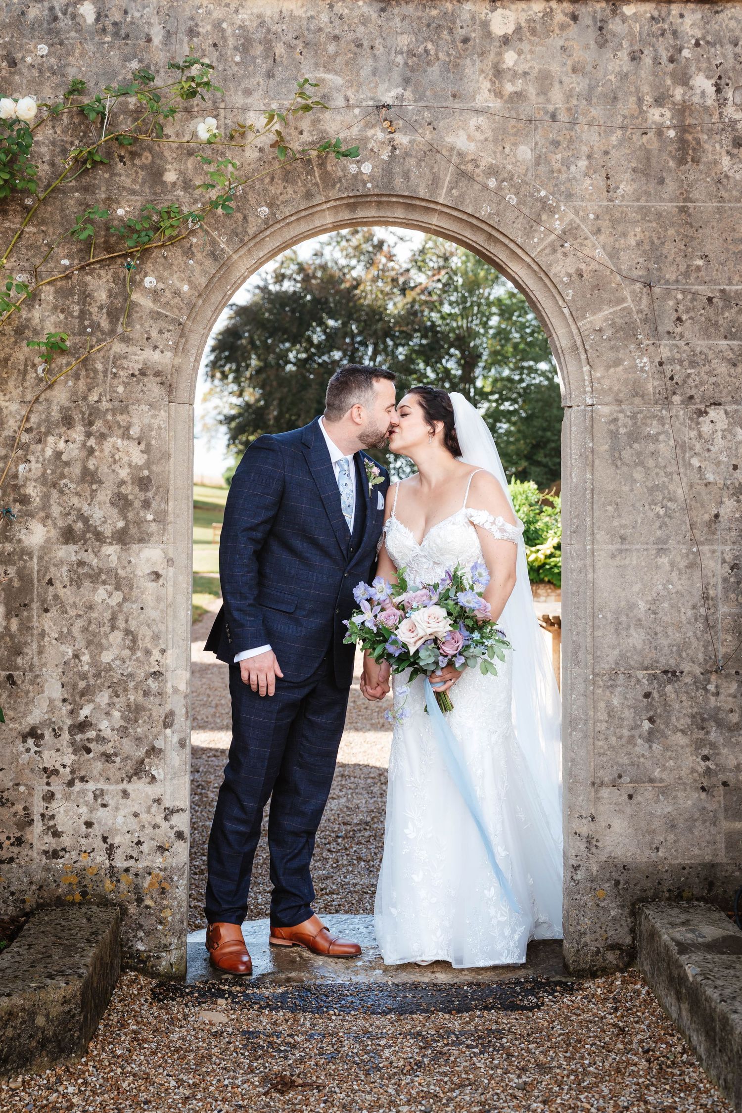 Coombe Lodge Wedding Photographer Zara Davis Photography bride and groom kissing beneath arch romantic somerset