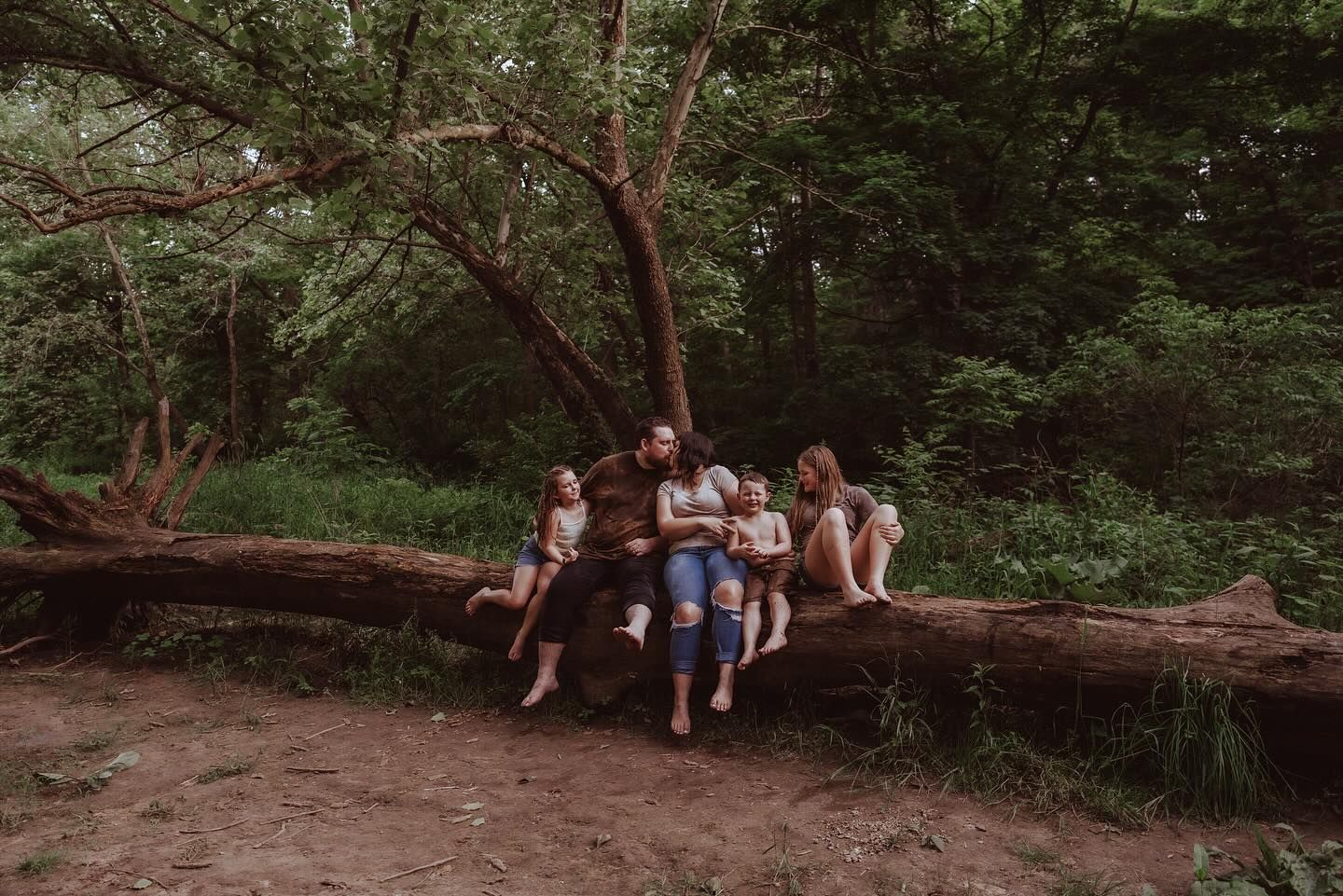Friends relaxing on fallen logs in a lush forest setting.