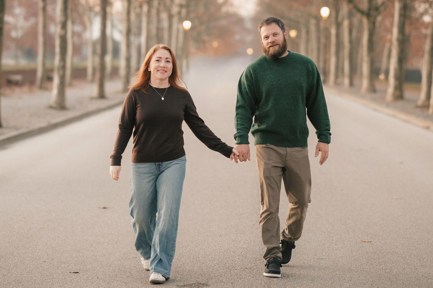 a man and woman walking down a path with trees on the side of the paths