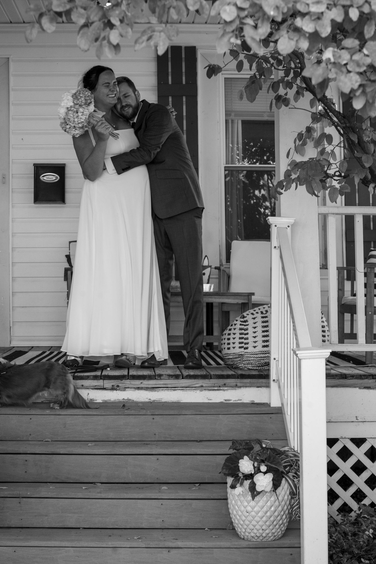 A romantic black and white wedding moment captured on a charming farmhouse porch with floral vines and lattice details.