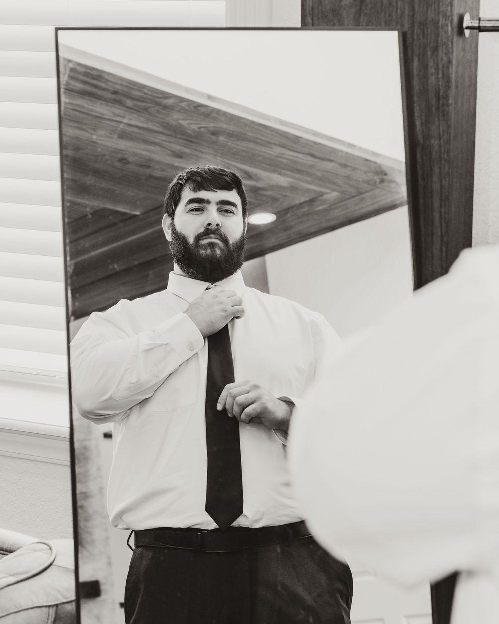 A sequence of four black and white photos showing a person in formal attire expressing different facial expressions.