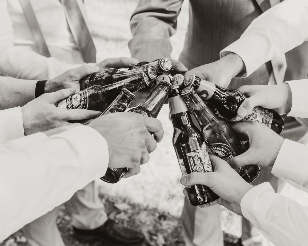 Black and white closeup of hands popping champagne bottles at celebration.