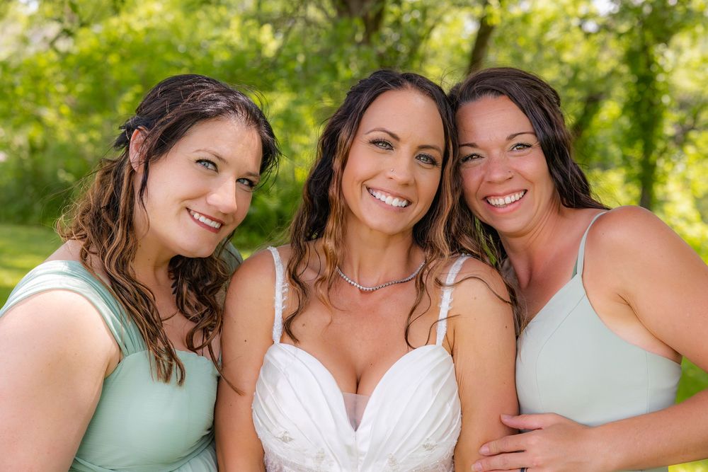 A group of bridesmaids in mint green dresses smile together during an outdoor summer wedding photo session.
