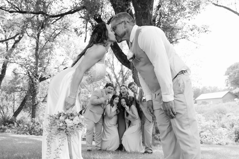 Two people share an intimate moment in a tranquil garden setting, captured in black and white photography.