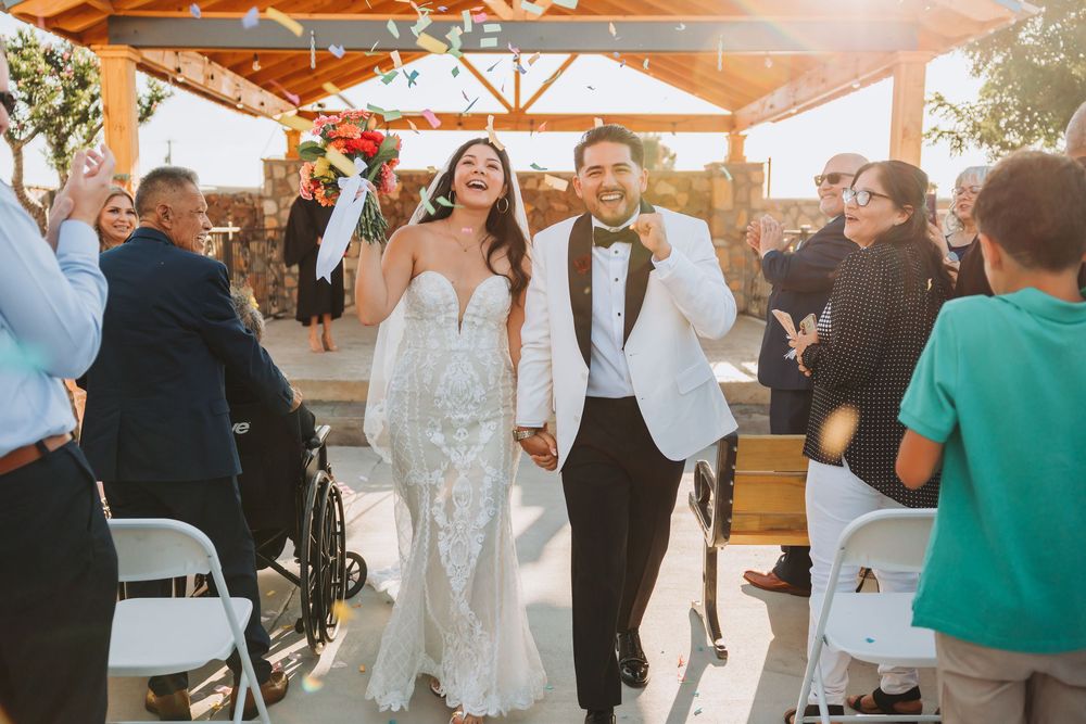 Wedding guests mingle and dance under an outdoor gazebo during a sunset celebration at a summer reception.