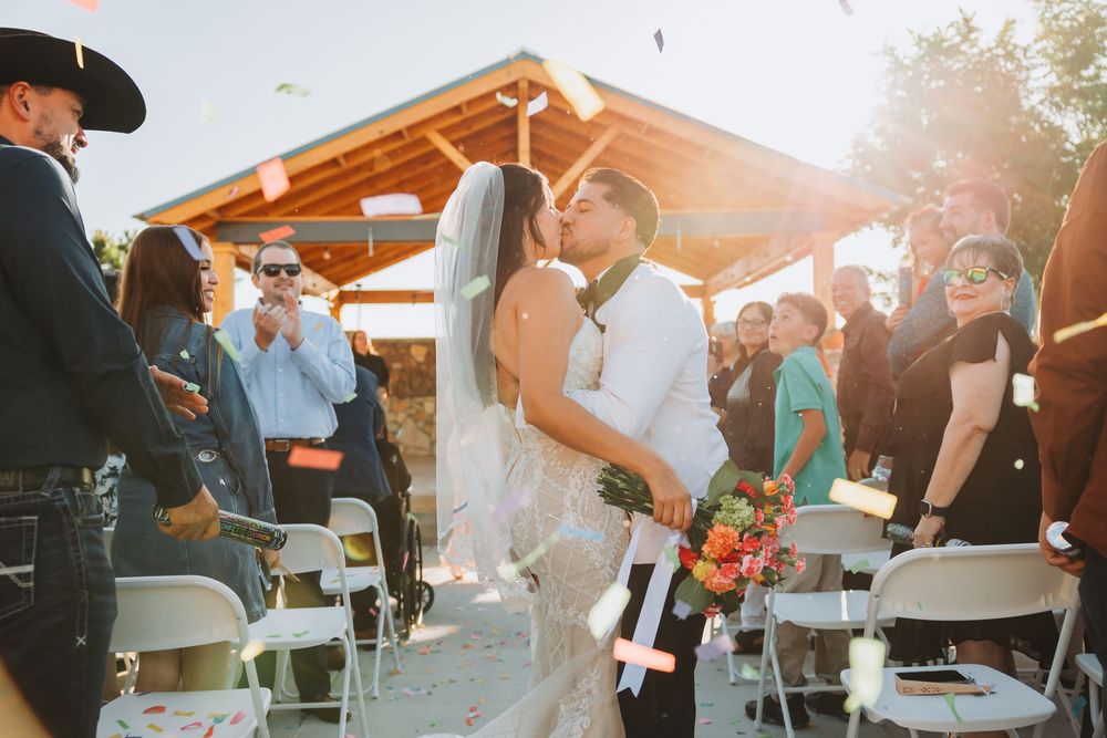 Wedding guests enjoy refreshments and conversation at an outdoor reception during golden hour sunset.