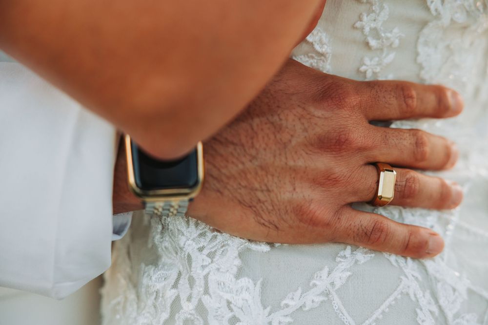 Close-up of multiple hands placing delicate lace appliques or embellishments onto white fabric in a meticulous process.