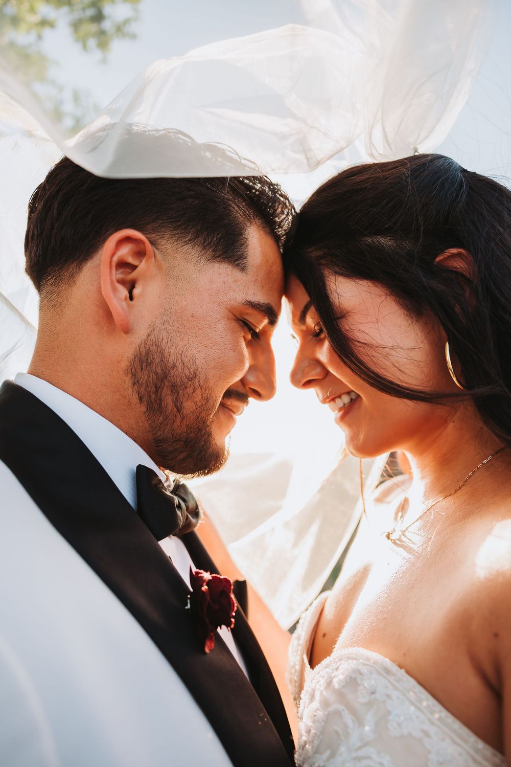 Close-up romantic portraits of a couple on their wedding day with sun-lit backlighting and intimate poses.