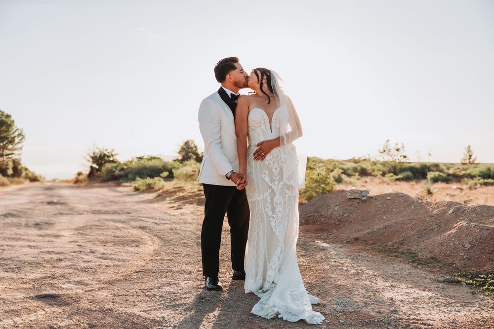 Newlywed couple embraces at sunset in a desert landscape with mountains in the background during their golden hour session.