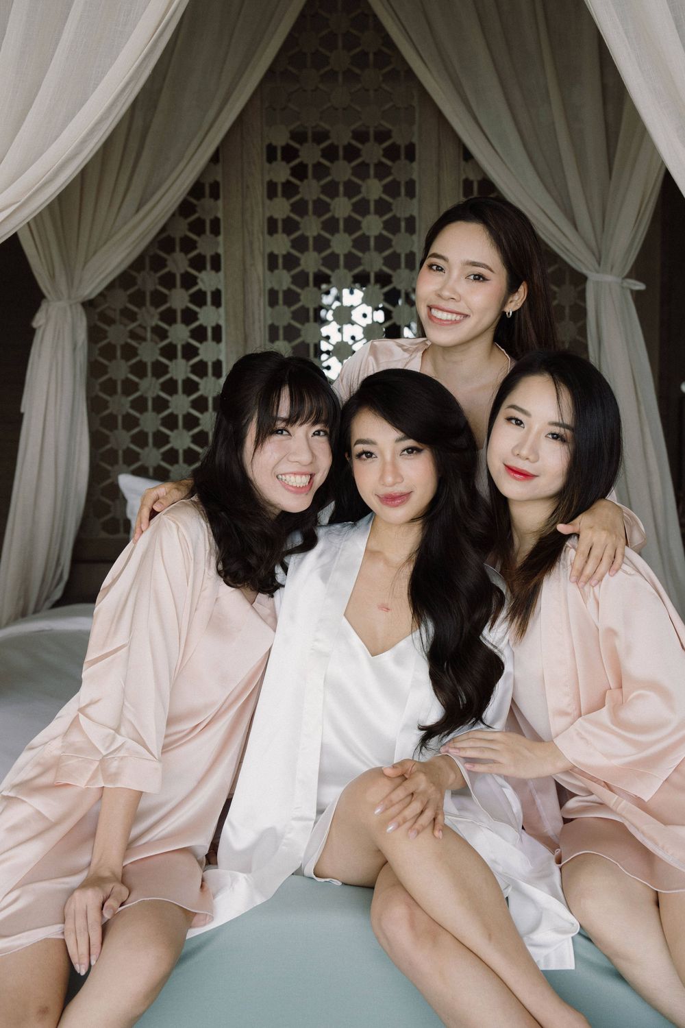 A group wearing matching pink and white robes pose together in an elegant draped setting.
