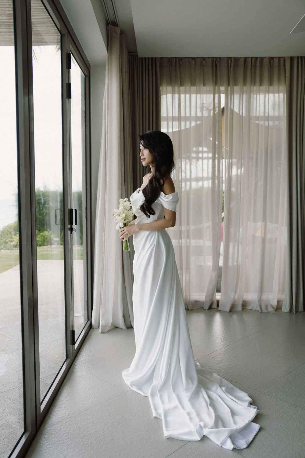 A series of elegant photos showing a flowing white wedding dress near floor-to-ceiling windows with sheer curtains.