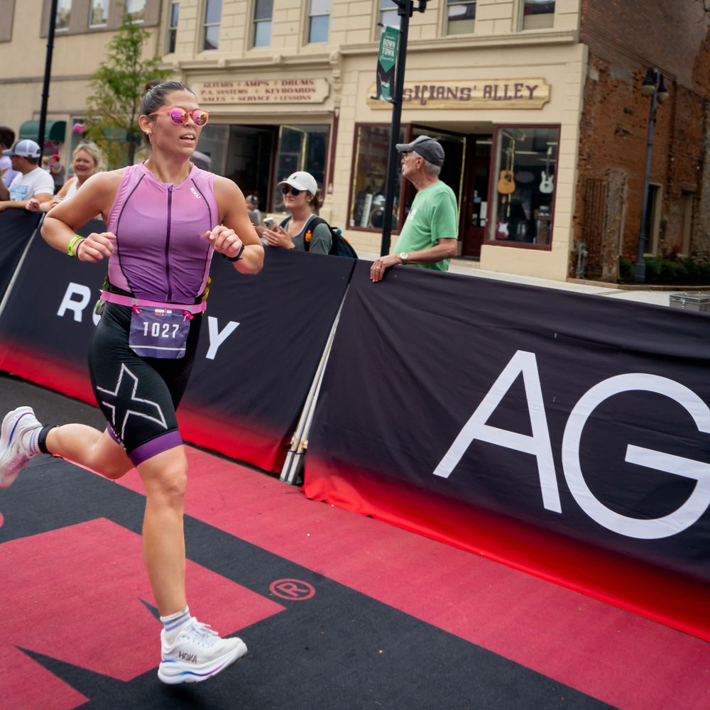 Athletic competitor finishes a running race on a red mat during an outdoor competition setup.