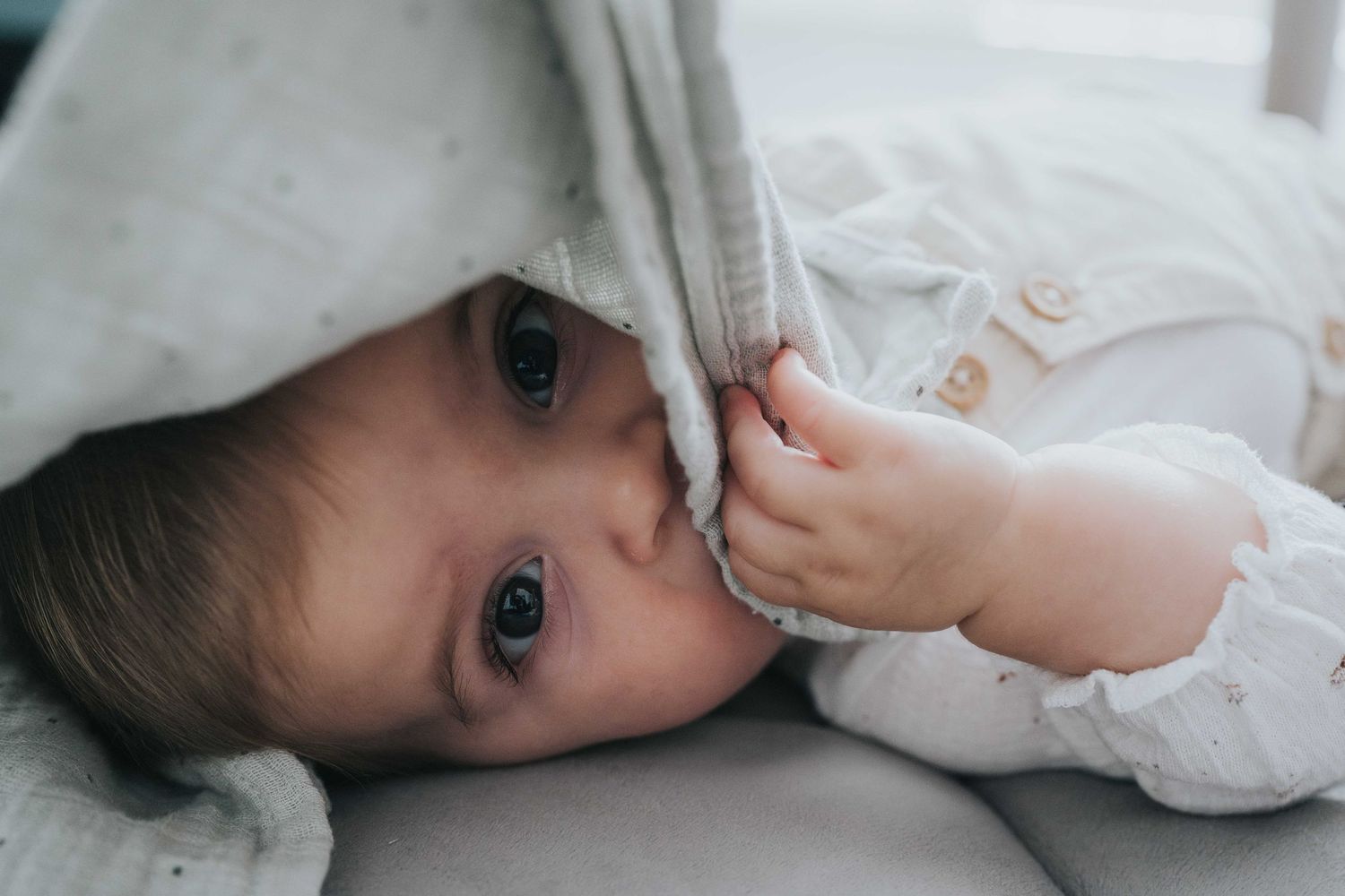 fotografia de familia en Alpedrete. Bebe tumbada escondiendo en el pañuelo. familia monoparental. menuda mirada