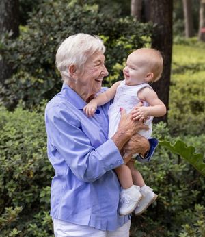 A joyful moment shared between a senior woman and a baby in a garden.