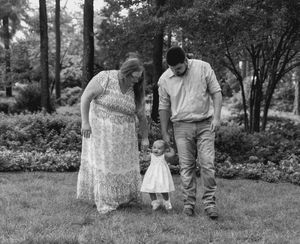 Family walking together through a wooded area in black and white.