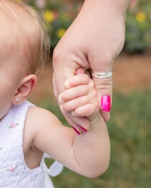 Close-up shots of hands holding and touching a baby's arm with pink nail polish visible.
