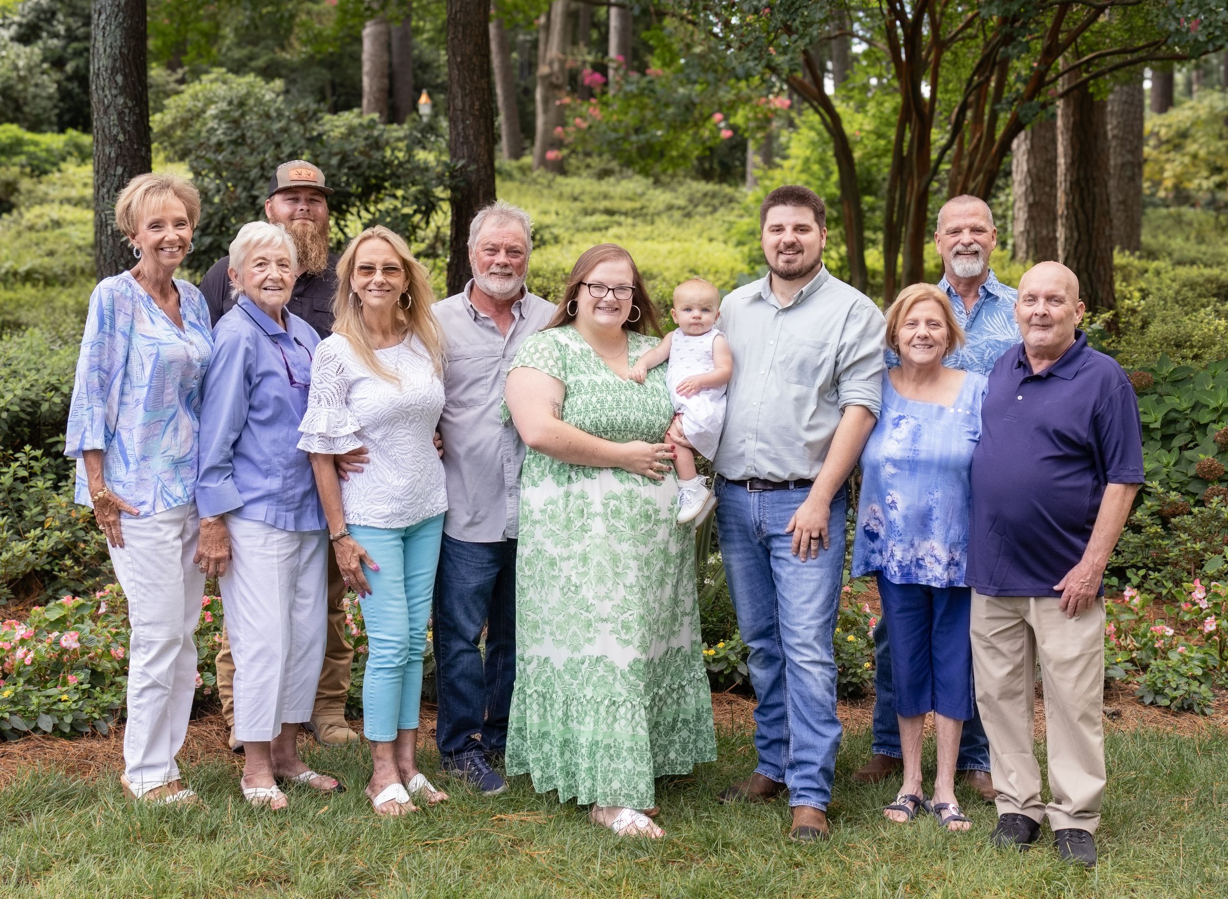 Large extended family group portrait outdoors in a garden setting.