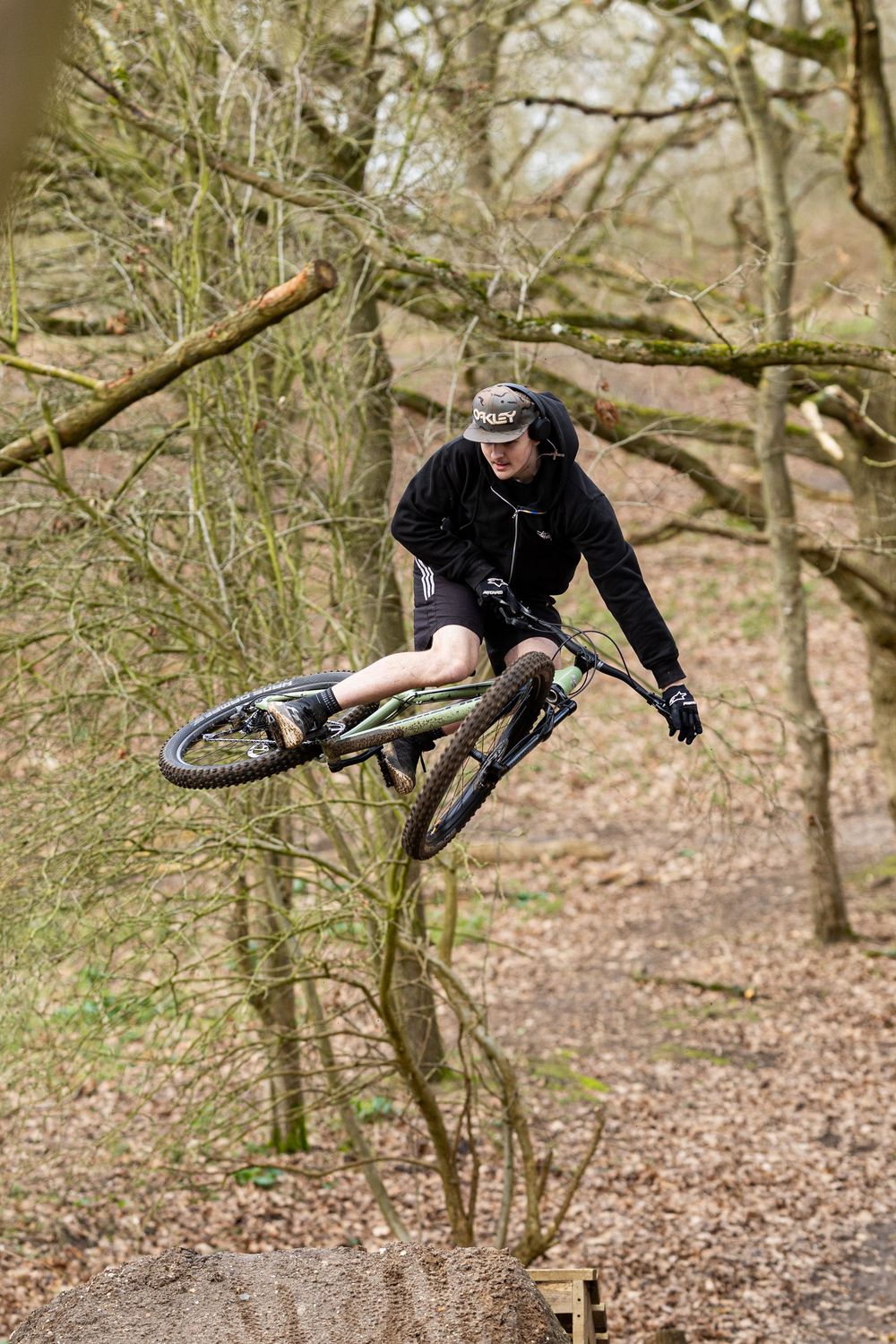 Mountain biker performs impressive aerial tricks through a wooded trail showing progressive sequence of jumps.