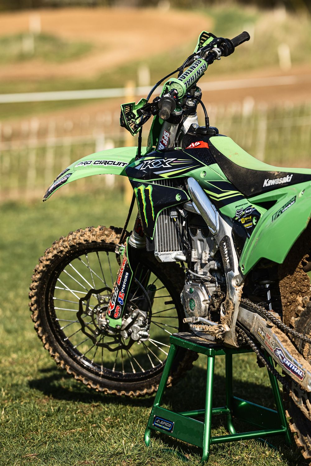 Close-up views of a green Kawasaki dirt bike showing engine and frame details on grass.