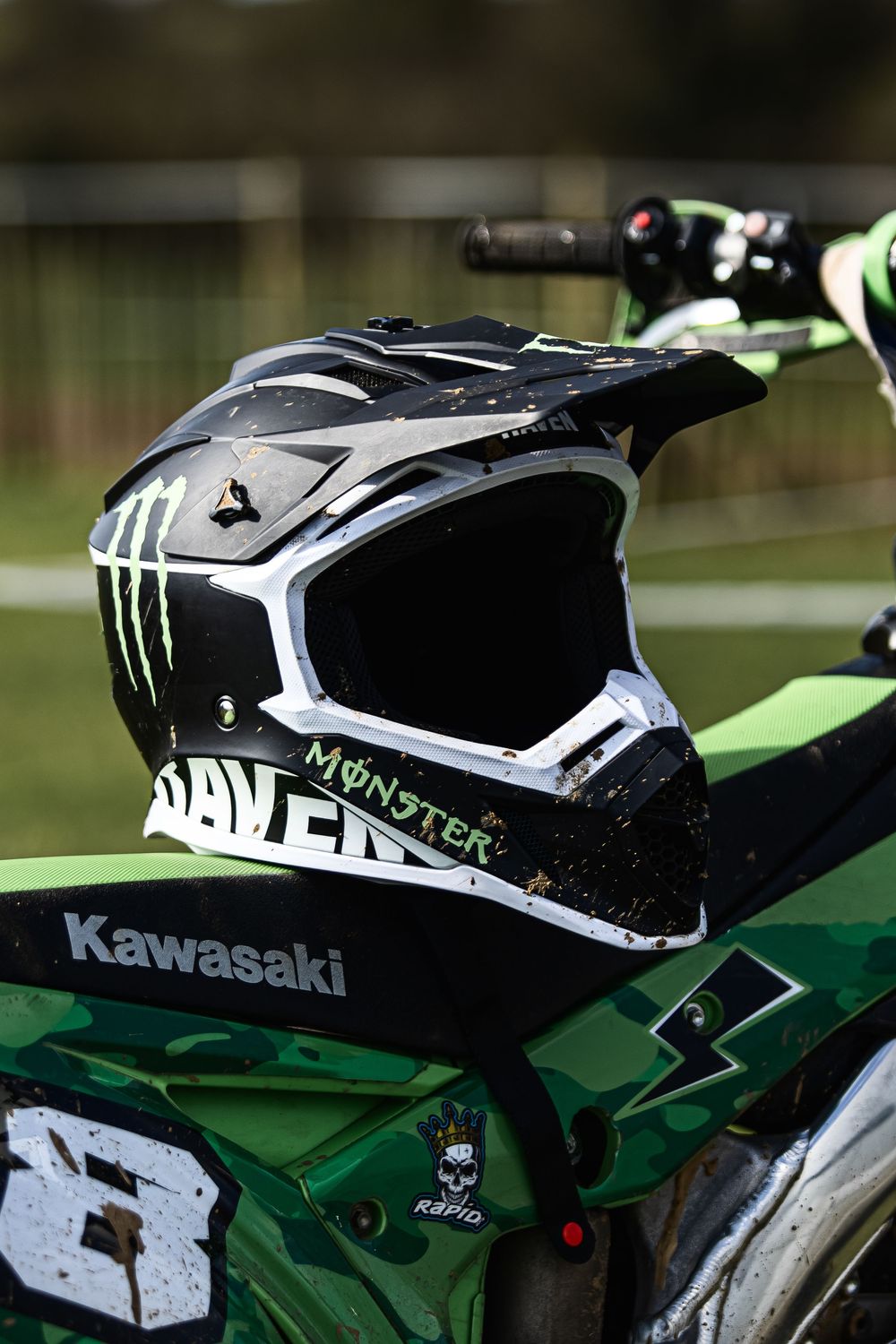 Close-up shots of a black Monster Energy branded Kawasaki dirt bike helmet with white accents.