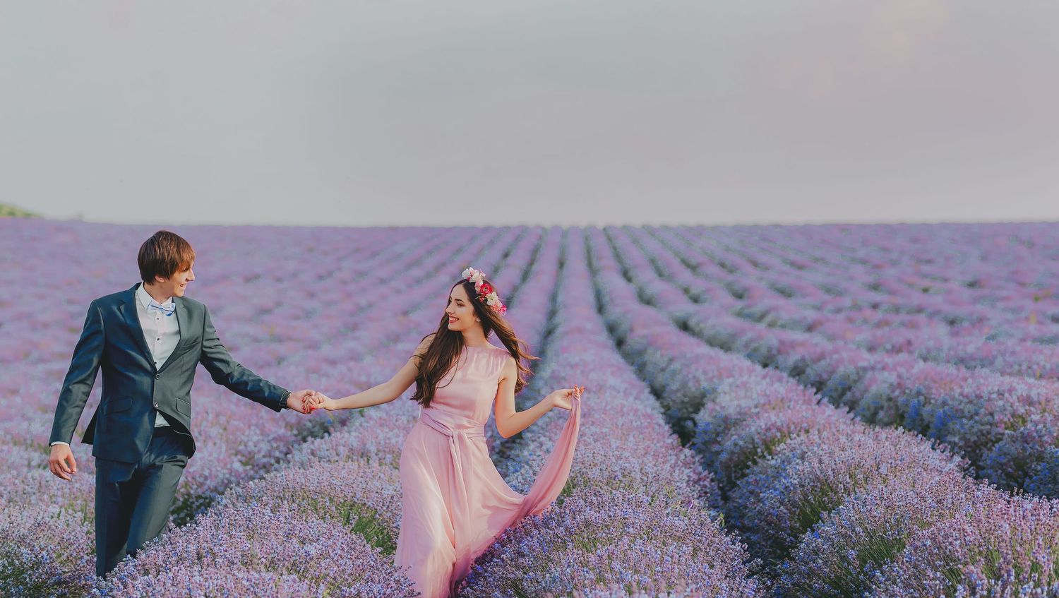 A couple enjoys a romantic photoshoot among rows of blooming purple lavender fields in Provence, France.