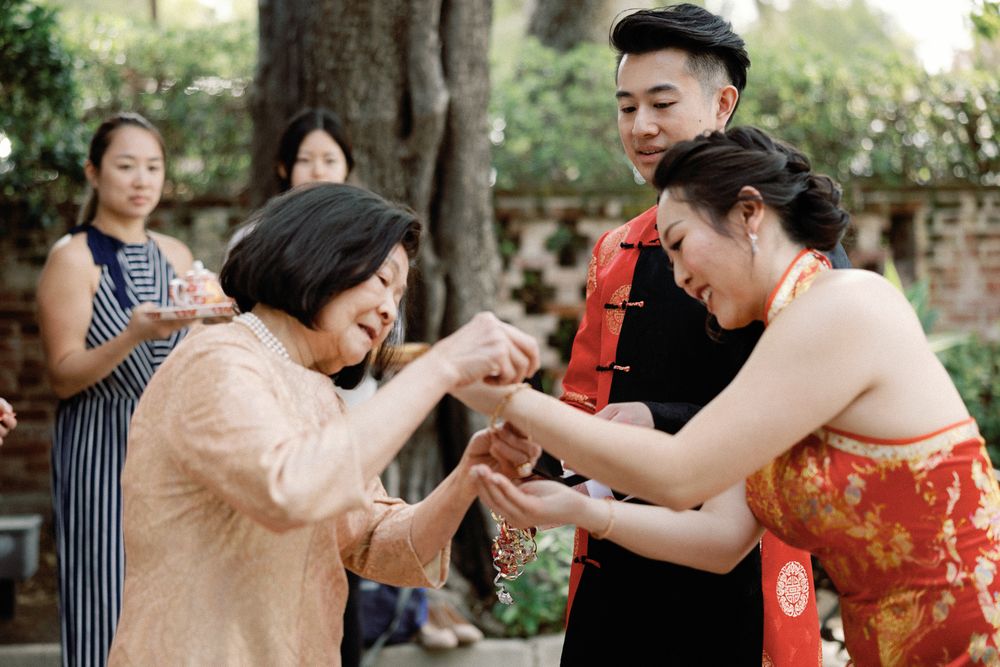 Family members sharing a joyful moment during a traditional Chinese tea ceremony outdoors.