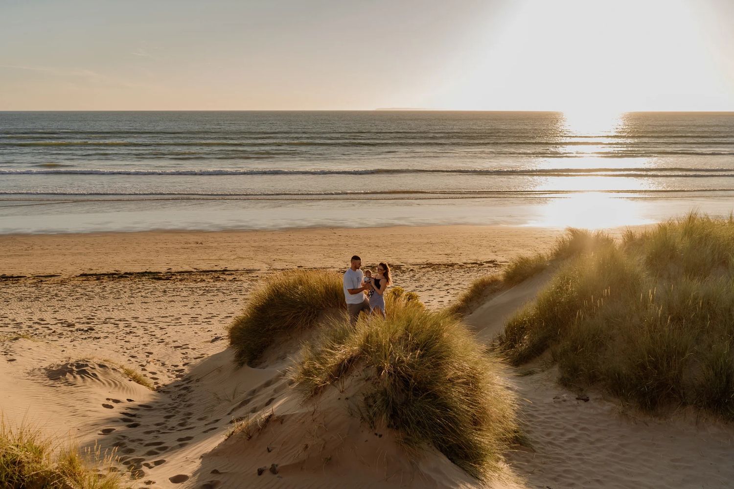 Seven scenic photographs of sandy beach dunes and ocean waves at sunset create a panoramic coastal landscape view.
