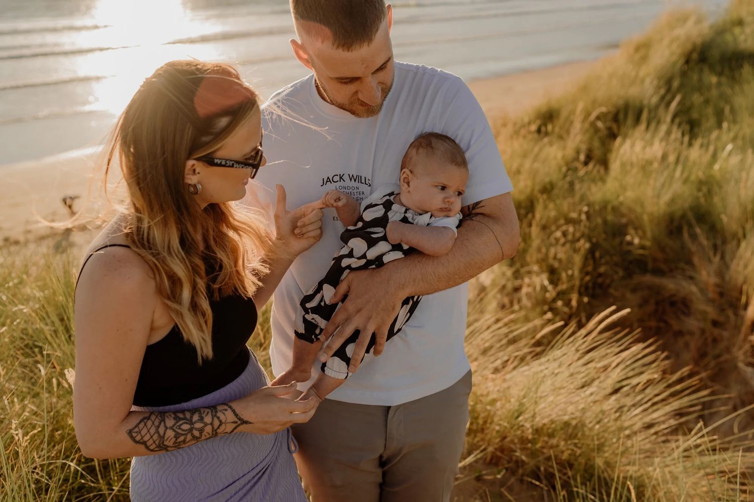 Family enjoying a tender moment together during golden hour sunset photoshoot on a sandy beach.