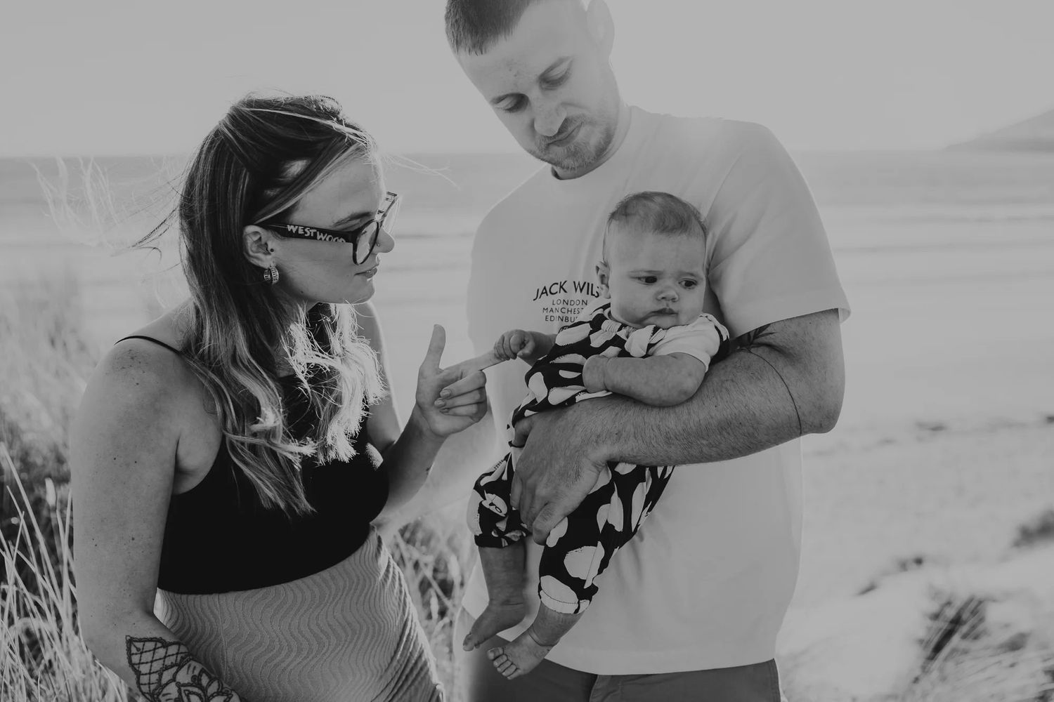 A collage of black and white maternity photos showing intimate moments during pregnancy at the beach.