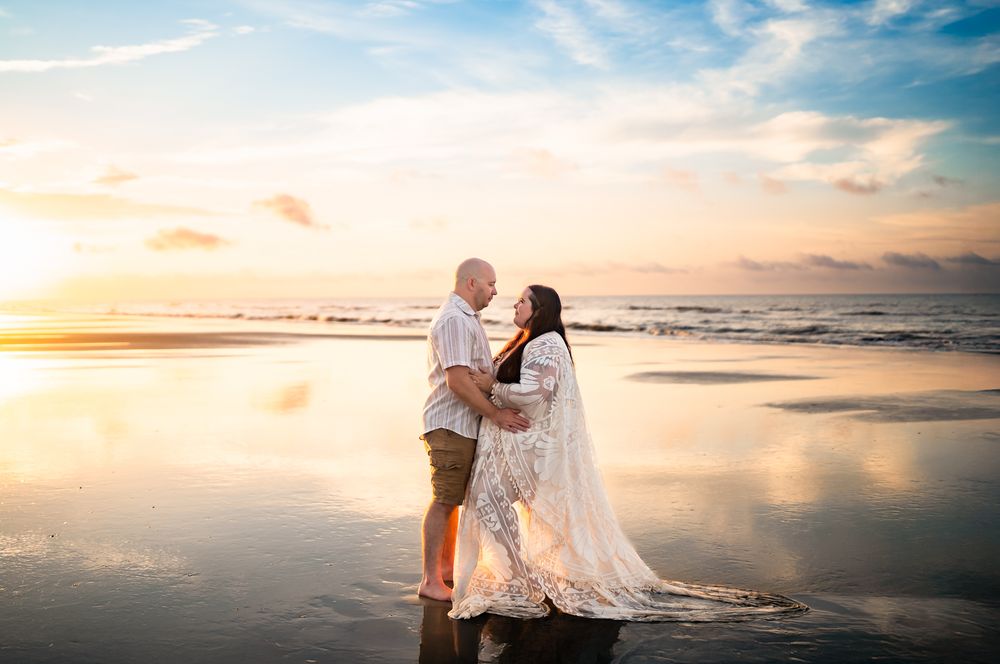 Newlywed couple shares romantic moments at sunset on a serene beach with waves gently rolling in the background.