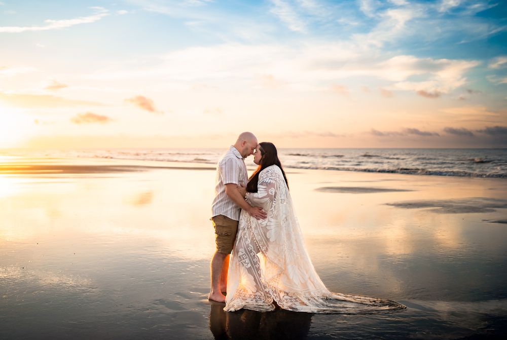 Panoramic beach scene with soft waves and warm sunset colors reflecting on the wet sand.