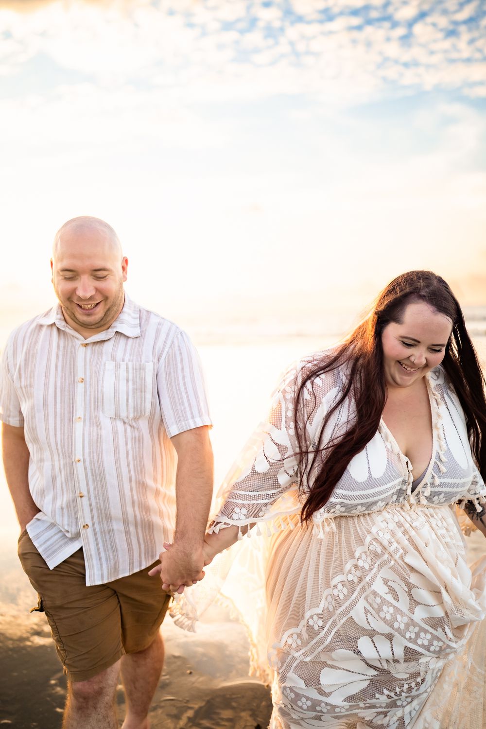A couple shares joyful moments together in a sun-drenched field at sunset with a dreamy golden glow.