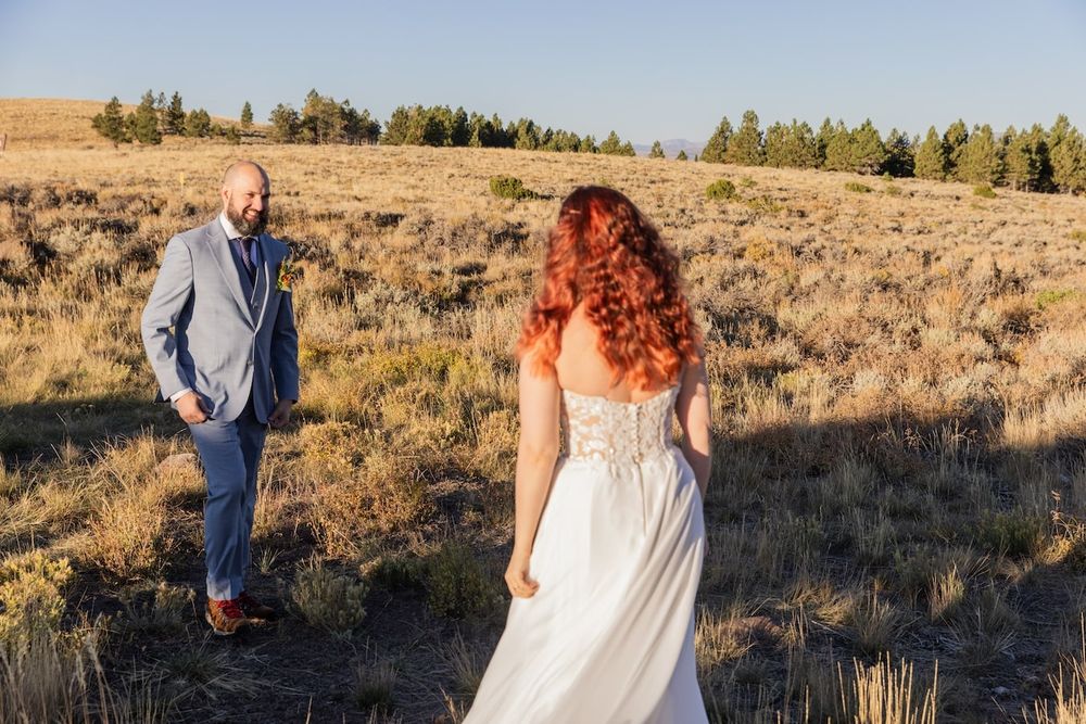 A wedding couple stands in a desert landscape with sagebrush during golden hour in a romantic outdoor setting.