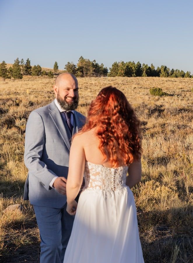 Outdoor wedding couple embraces in golden desert landscape during sunset wedding ceremony in Oregon.