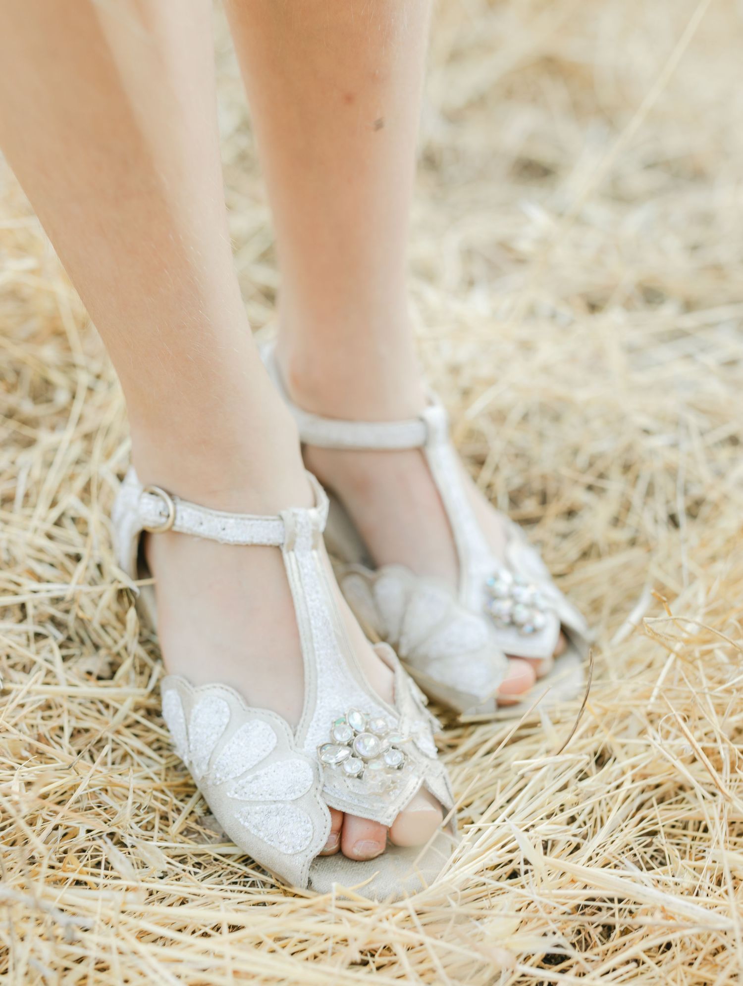 Ballet dancer in white dress performs graceful arabesque pose in golden field at sunset, wearing sneakers captured by Chelsee Rawe Photogra.