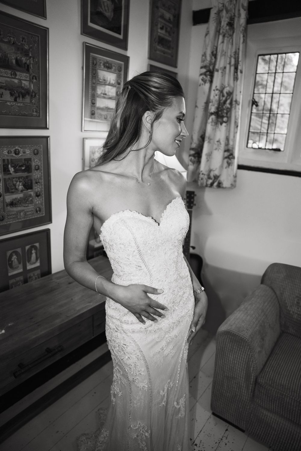 Black and white photos show someone adjusting a white lace wedding gown in an indoor setting with framed artwork.