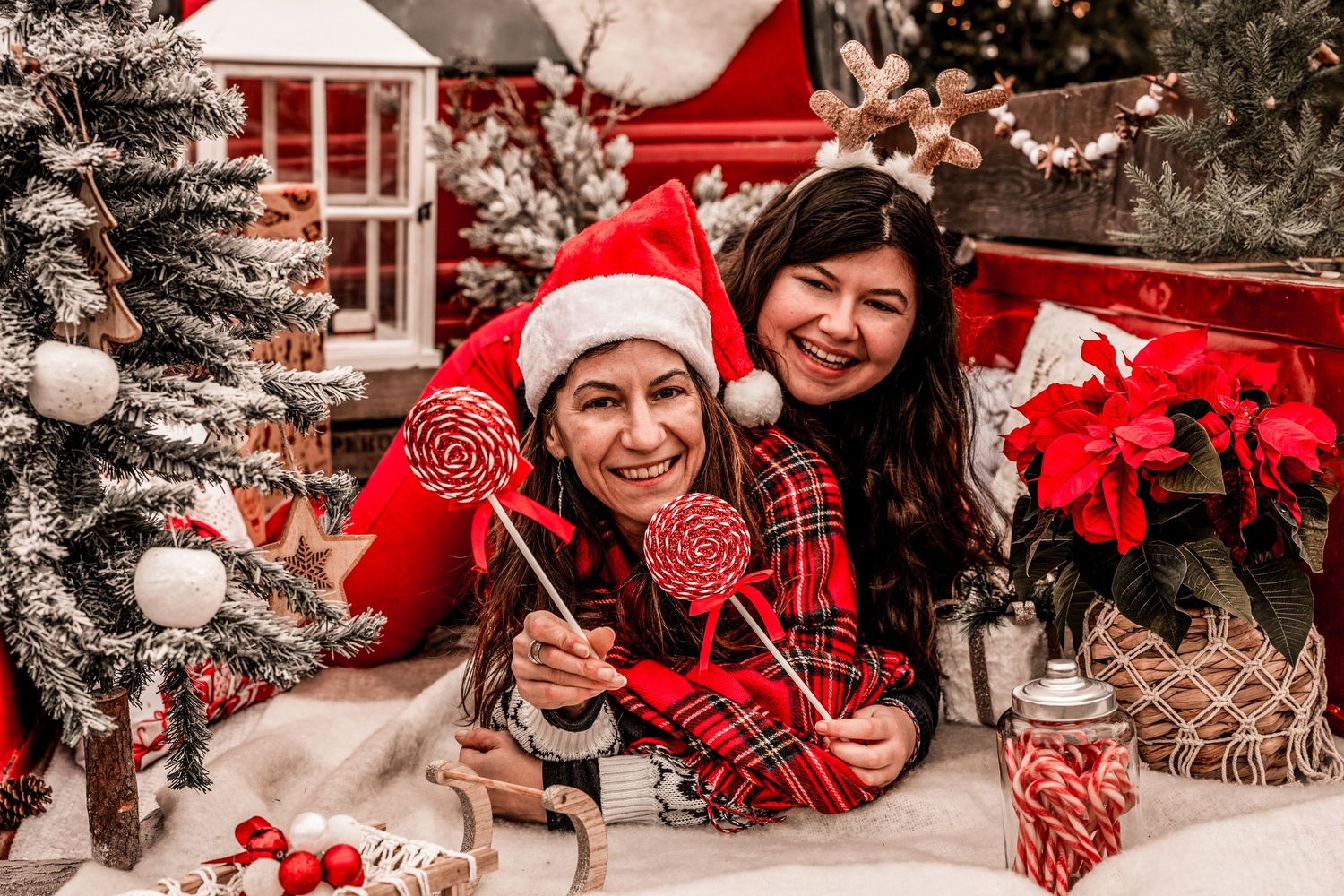 Cozy Christmas scene with people in red and white holiday attire surrounded by decorated trees and wrapped gifts.
