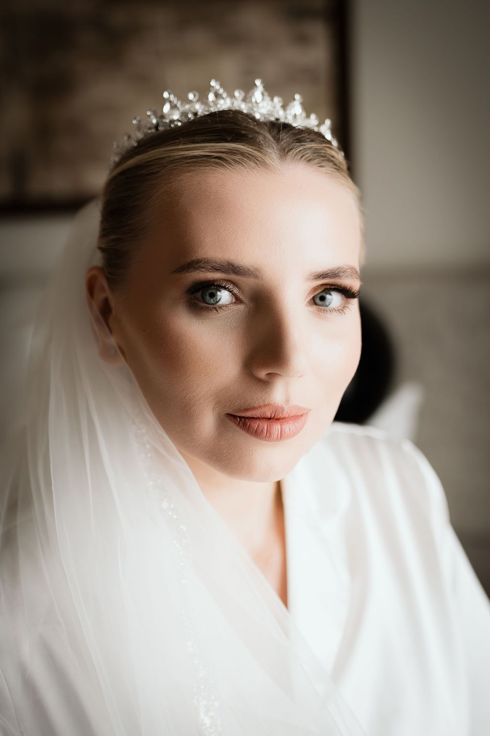 Beautiful bridal portrait featuring a delicate crystal tiara and flowing white veil with soft natural makeup.