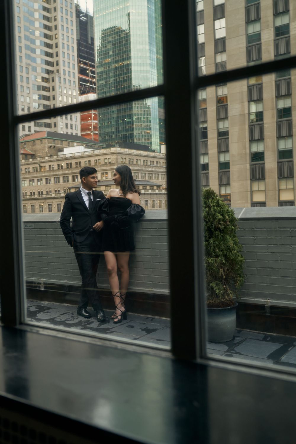 A couple in formal attire shares an intimate moment on a rooftop terrace with city buildings in the background by 3 West Club manhattan