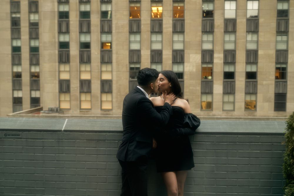 A romantic embrace on a rooftop with an urban backdrop of tall buildings at dusk by 3 West Club manhattan