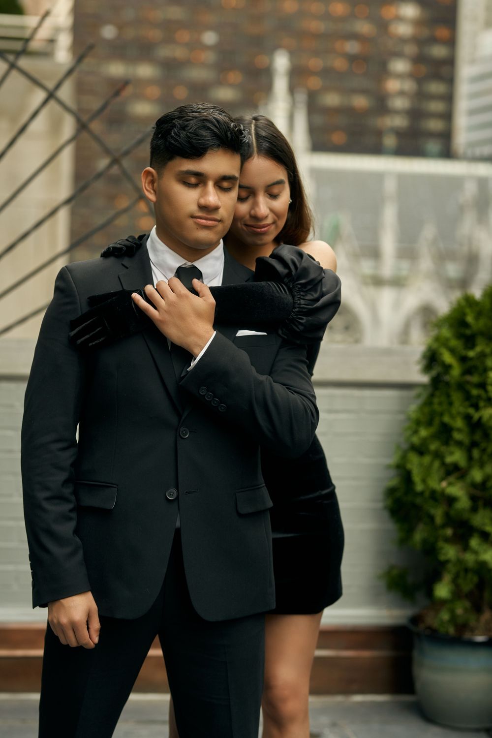 A romantic couple dressed in black formal attire embraces while posing for photos outdoors by 3 West Club manhattan