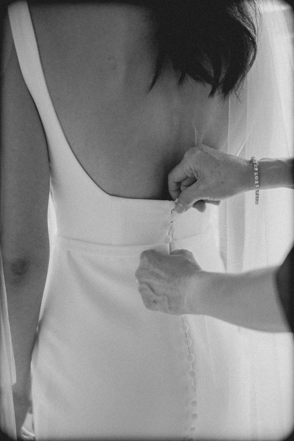 Artistic black and white close-up shots showing different angles of a modern white wedding dress with delicate button details.