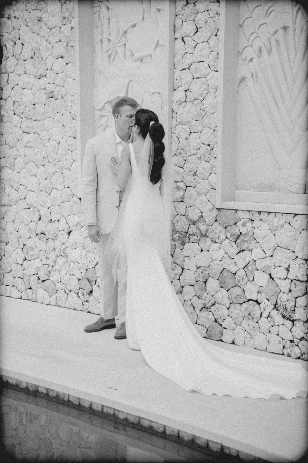 Black and white sequence of wedding dress train details against a textured stone wall.