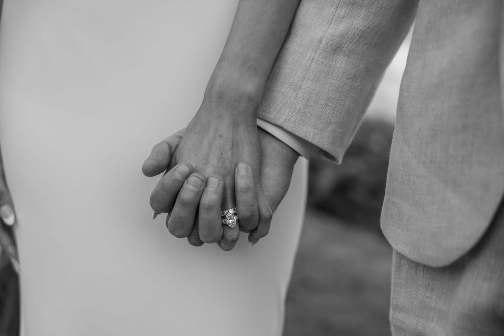 Black and white detail photo of hands holding champagne glasses during a wedding celebration toast.